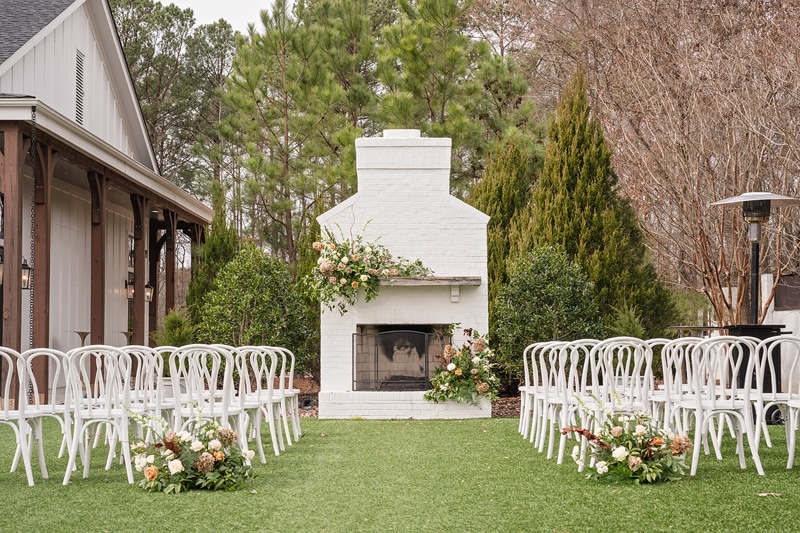 A wedding ceremony at The Bradford with a white chairs and a fireplace.