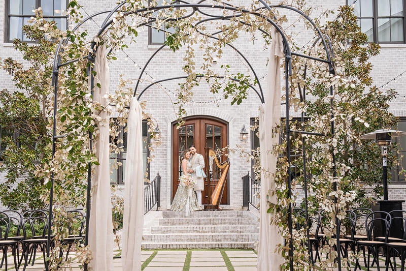 The bride and groom are standing in front of an archway at The Bradford Wedding Venue.