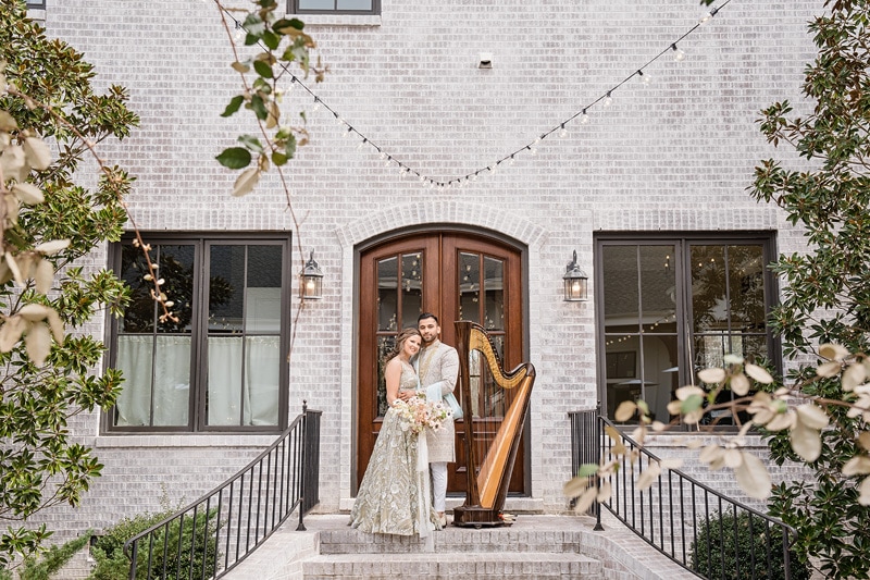 A bride and groom standing on the steps of The Bradford Wedding venue with a harp.
