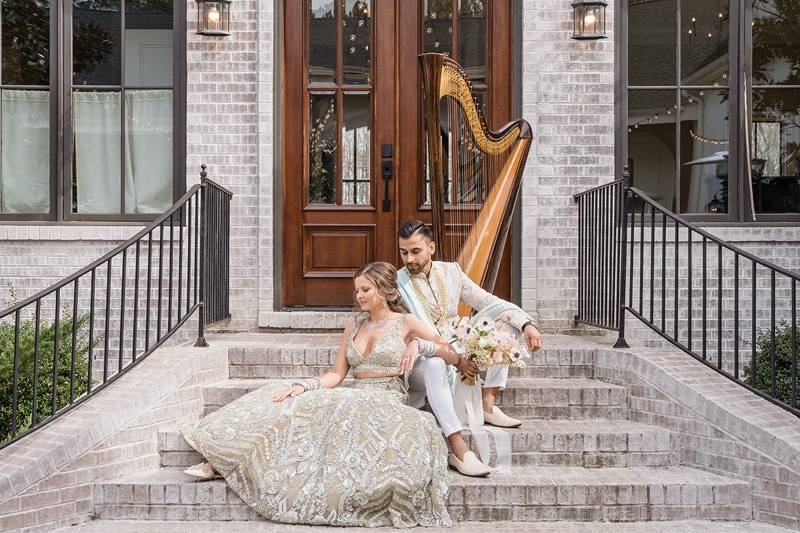 A bride and groom sitting on steps with a harp at The Bradford Wedding Venue.