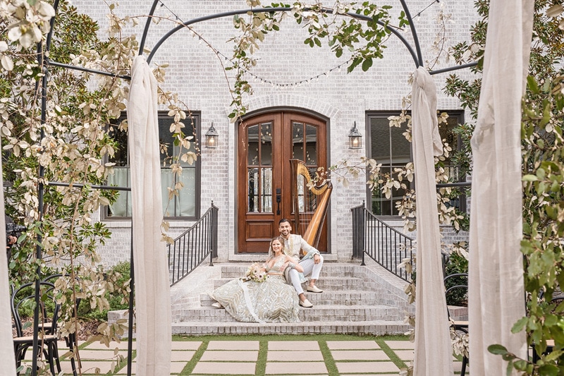 A bride and groom sitting on steps in front of The Bradford Wedding venue.