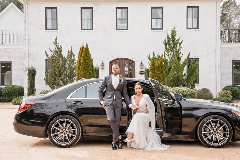 A bride and groom standing next to a black Mercedes Benz at The Bradford Wedding Venue.