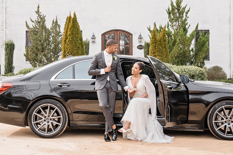 A bride and groom standing next to a black Mercedes-Benz at The Bradford Wedding Venue.