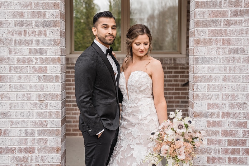 A bride and groom standing in front of a brick wall at The Bradford Wedding Venue.
