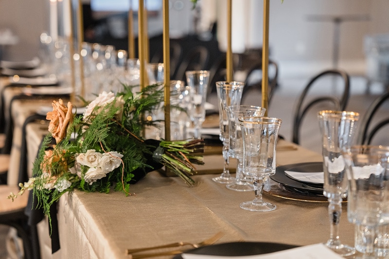 A black and gold table setting adorned with candles and flowers at The Bradford Wedding Venue.
