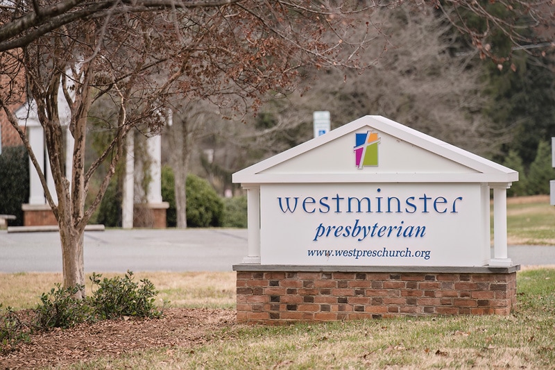 A sign for Westminster Presbyterian Church in front of a tree.