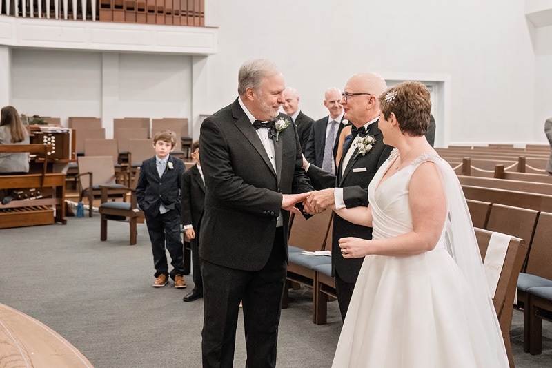 Brad and Shana, bride and groom, shaking hands at Westminster Presbyterian Church during their wedding.