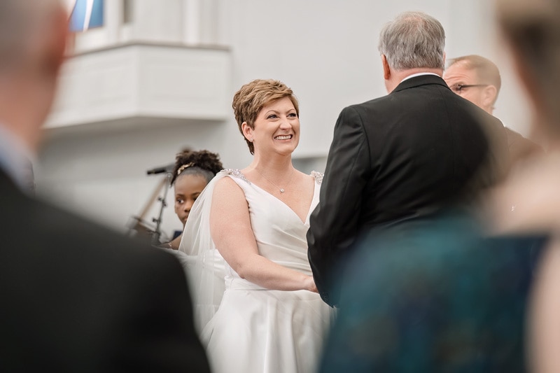 Brad and Shana, a bride and groom, smiling at each other during their wedding ceremony at Westminster Presbyterian Church.