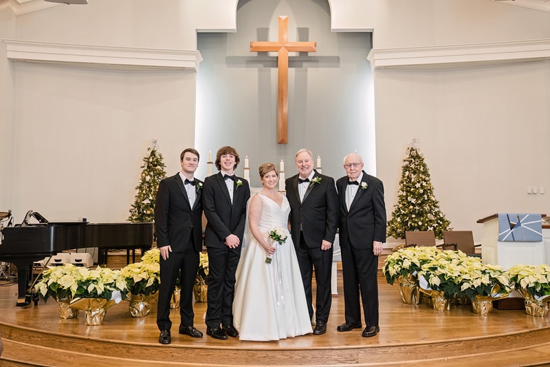 Brad and Shana's wedding party posing in front of a Christmas tree at Westminster Presbyterian Church Wedding.