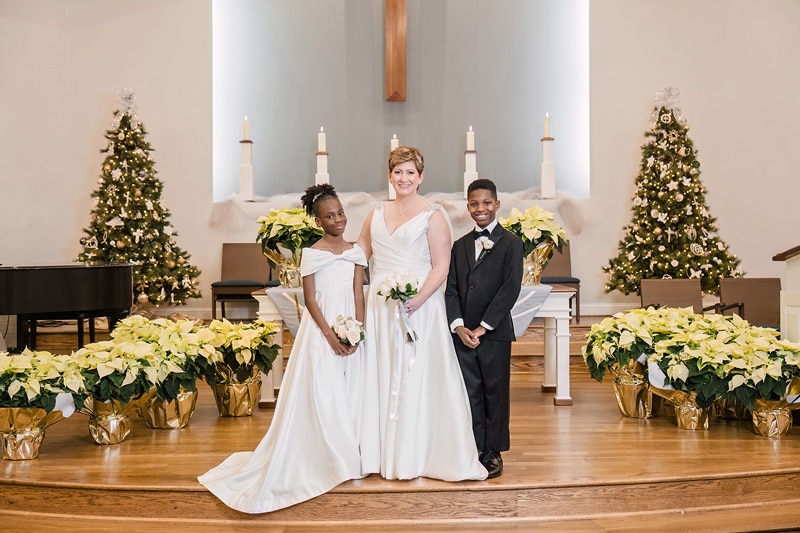 A bride and groom posing in front of Westminster Presbyterian Church with poinsettias.