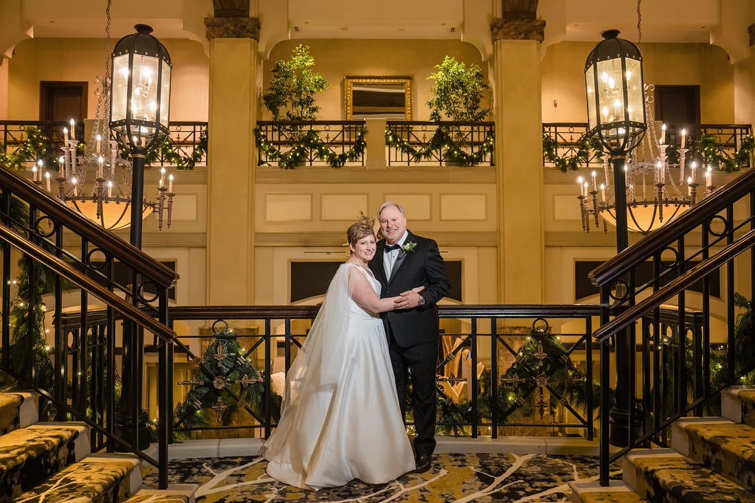 A bride and groom standing on the stairs of Grandover Resort & Spa, after their Westminster Presbyterian Church wedding.