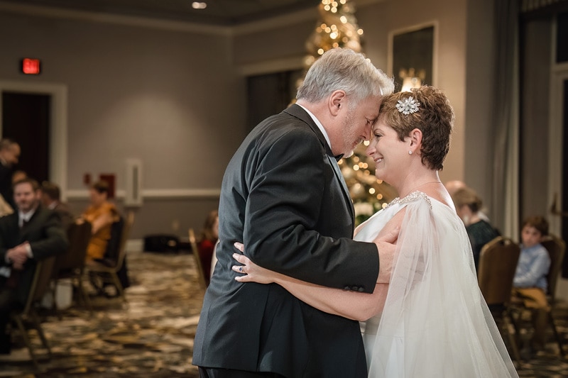 A bride and groom sharing their first dance in front of a Christmas tree at their Grandover Resort & Spa wedding reception.
