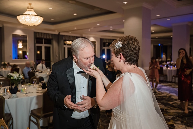 Brad and Shana, a bride and groom, feeding each other cake at their wedding reception held at the Grandover Resort & Spa.