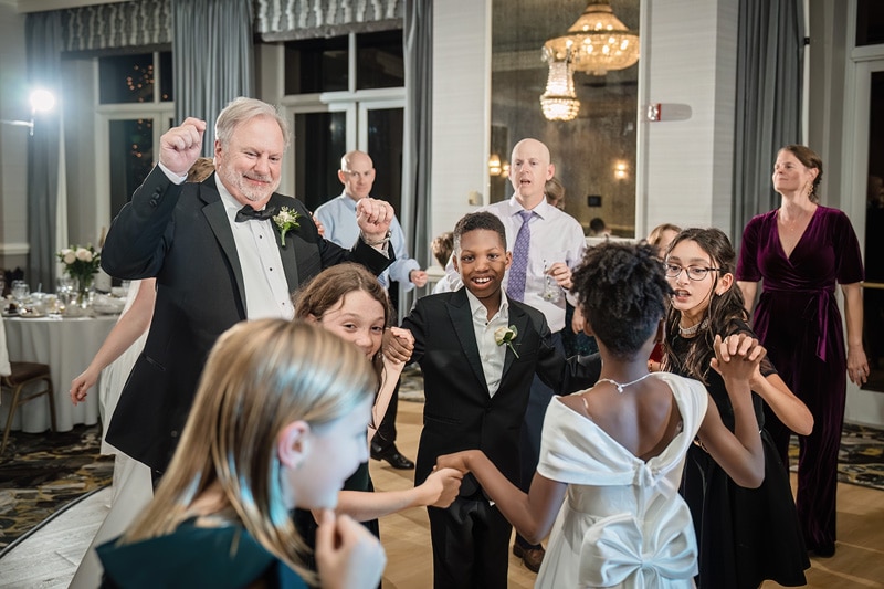 A group of people holding hands and dancing at a Grandover Resort & Spa wedding reception.