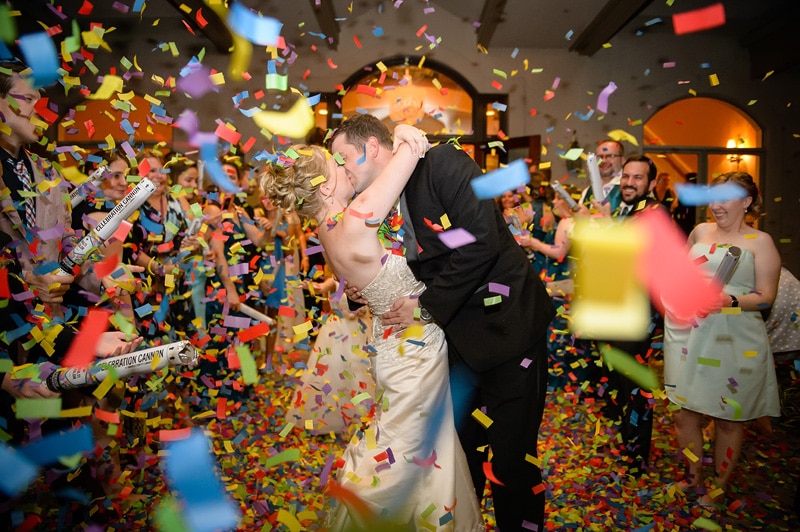 A bride and groom kissing under confetti at a Governors Club Wedding.