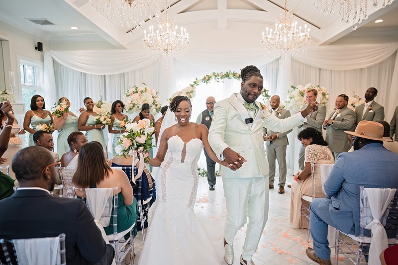 Bride and groom walk down the aisle in Crystal Ballroom Charlotte while guests applaud after a wedding ceremony.