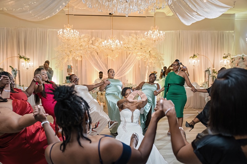 A bridal party is enthusiastically dancing and enjoying themselves at the Crystal Ballroom Charlotte during a wedding reception.