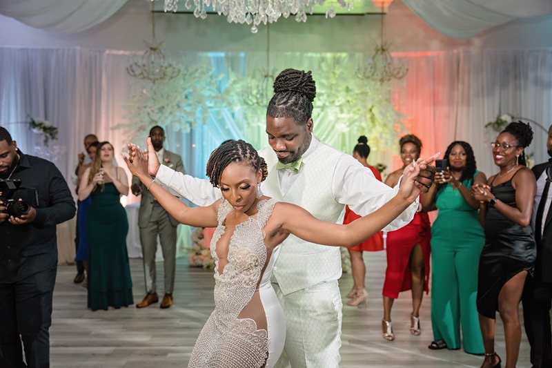 A couple dances joyfully in the Crystal Ballroom Charlotte while surrounded by applauding guests at a wedding reception.