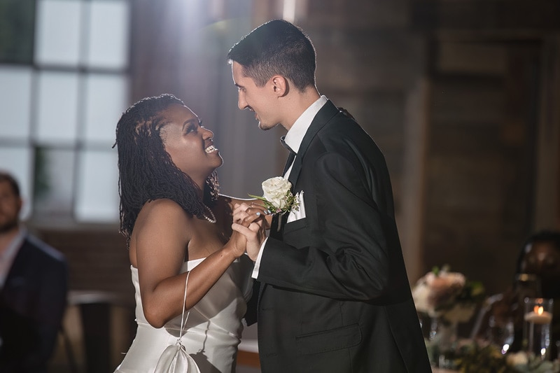 A joyful bride and groom share a tender moment during their first dance at The Rickhouse wedding reception, surrounded by the warm glow of candlelight, embodying the romance and elation of their wedding day