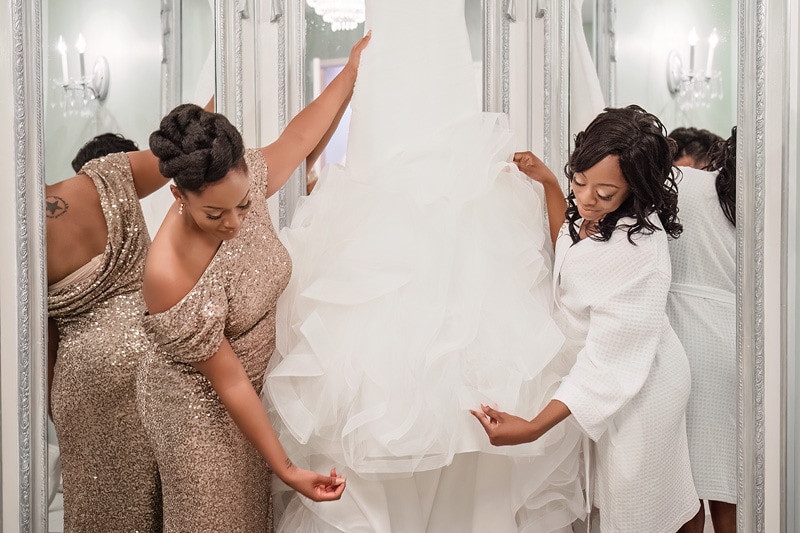 Two women admire and arrange a bridal gown for a Grand Marquise Ballroom wedding.