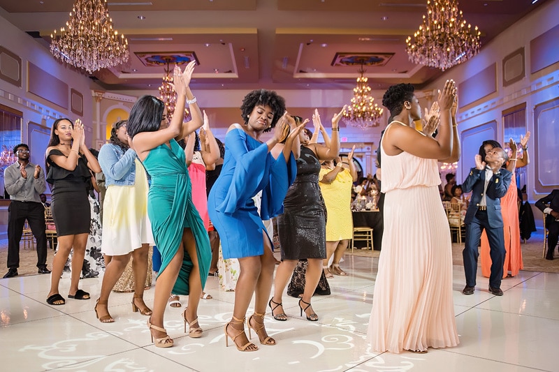 A group of women dancing together in the Grand Marquise Ballroom, under the glow of elegant chandeliers.