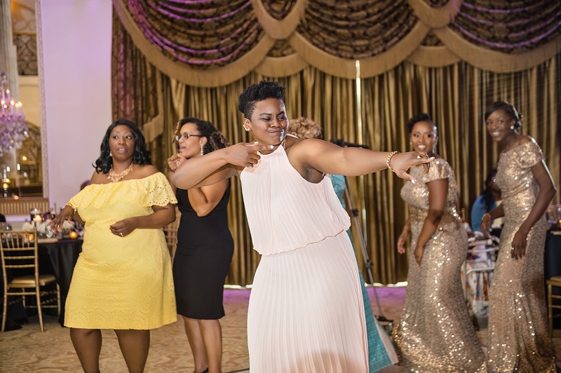 A group of women dressed in formal attire striking playful poses at a Grand Marquise Ballroom wedding.