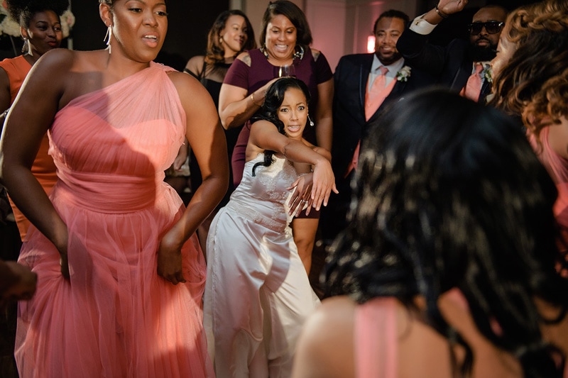A lively dance floor at a Paramount Event Venue wedding reception, with the radiant bride in white joyously moving to the music surrounded by elegantly dressed guests sharing in the celebration.