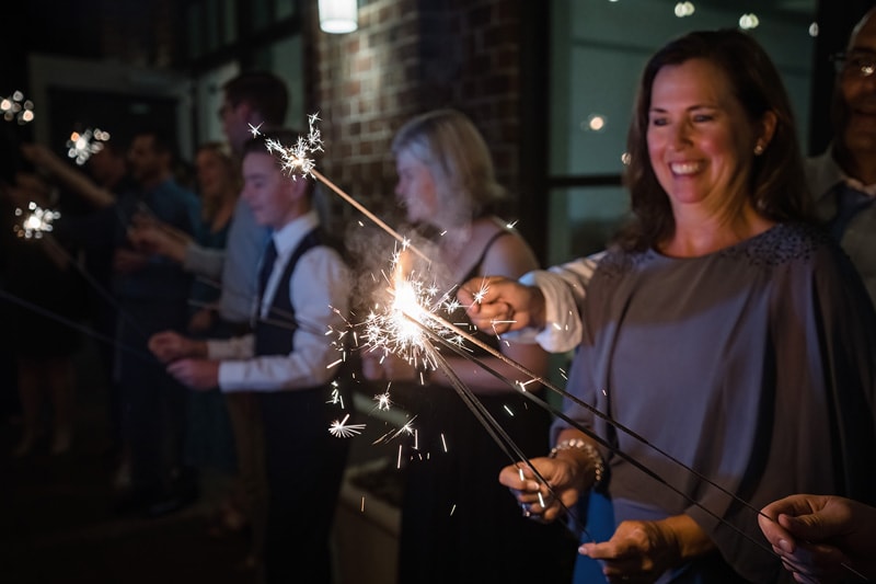 A joyous group of people holds sparkling sparklers at night at the Paramount Event Venue, creating a festive and illuminating celebration atmosphere.